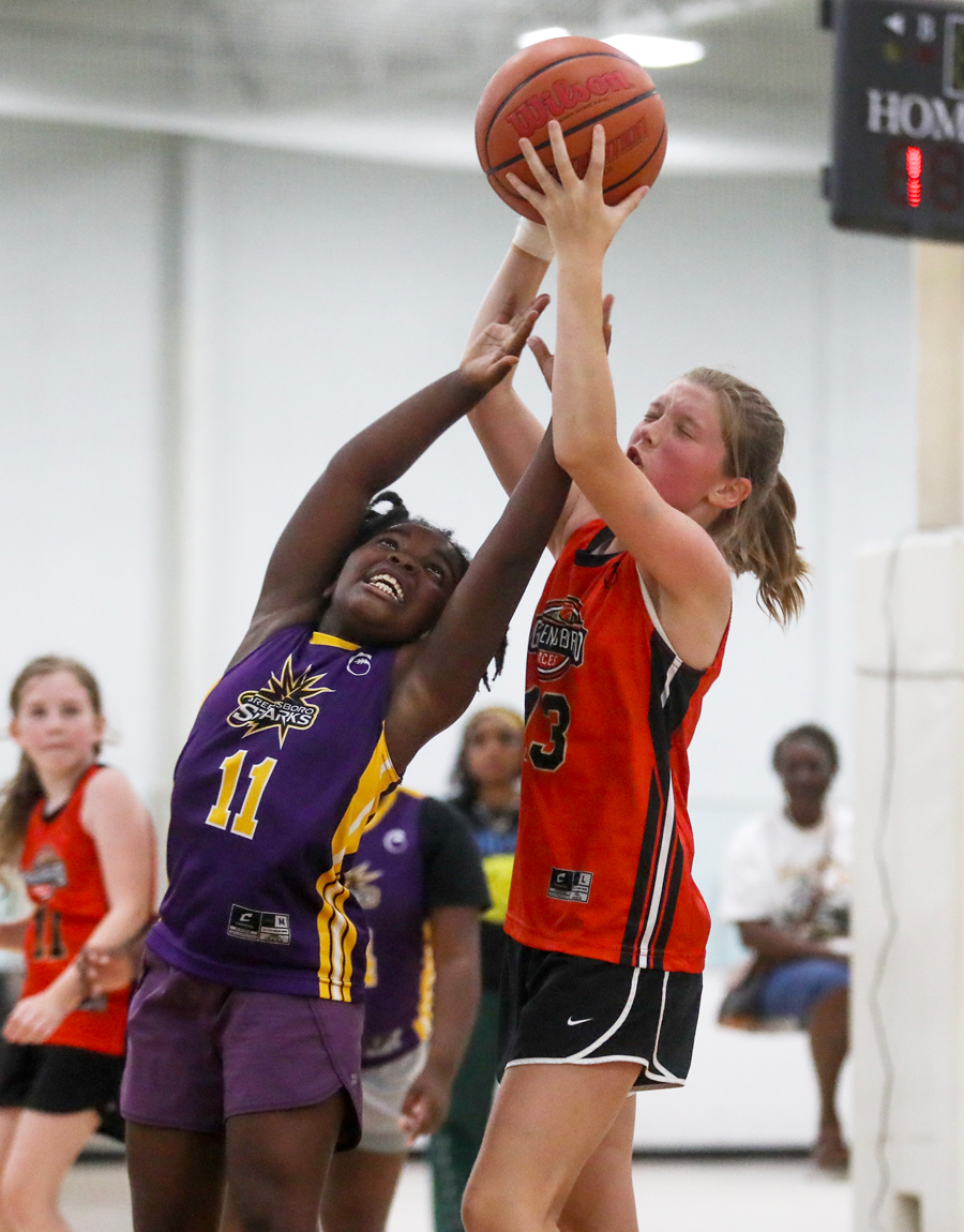 2 young girls jumping for a basketball